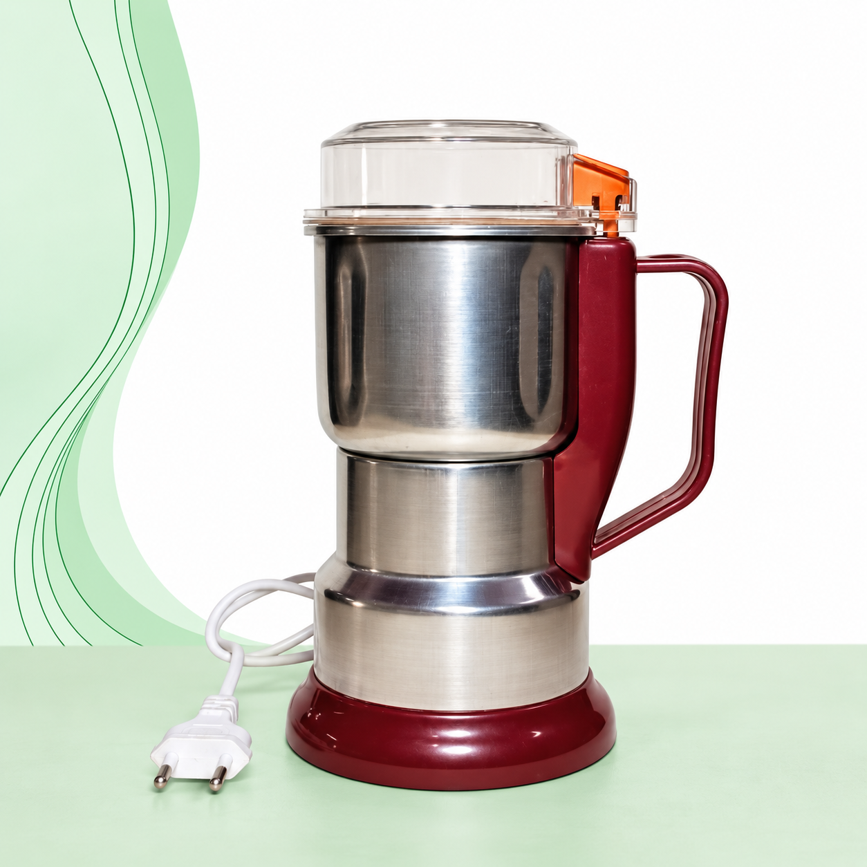 Silver and maroon electric spice grinder with a transparent lid, side handle and white power cord on a green wave background.